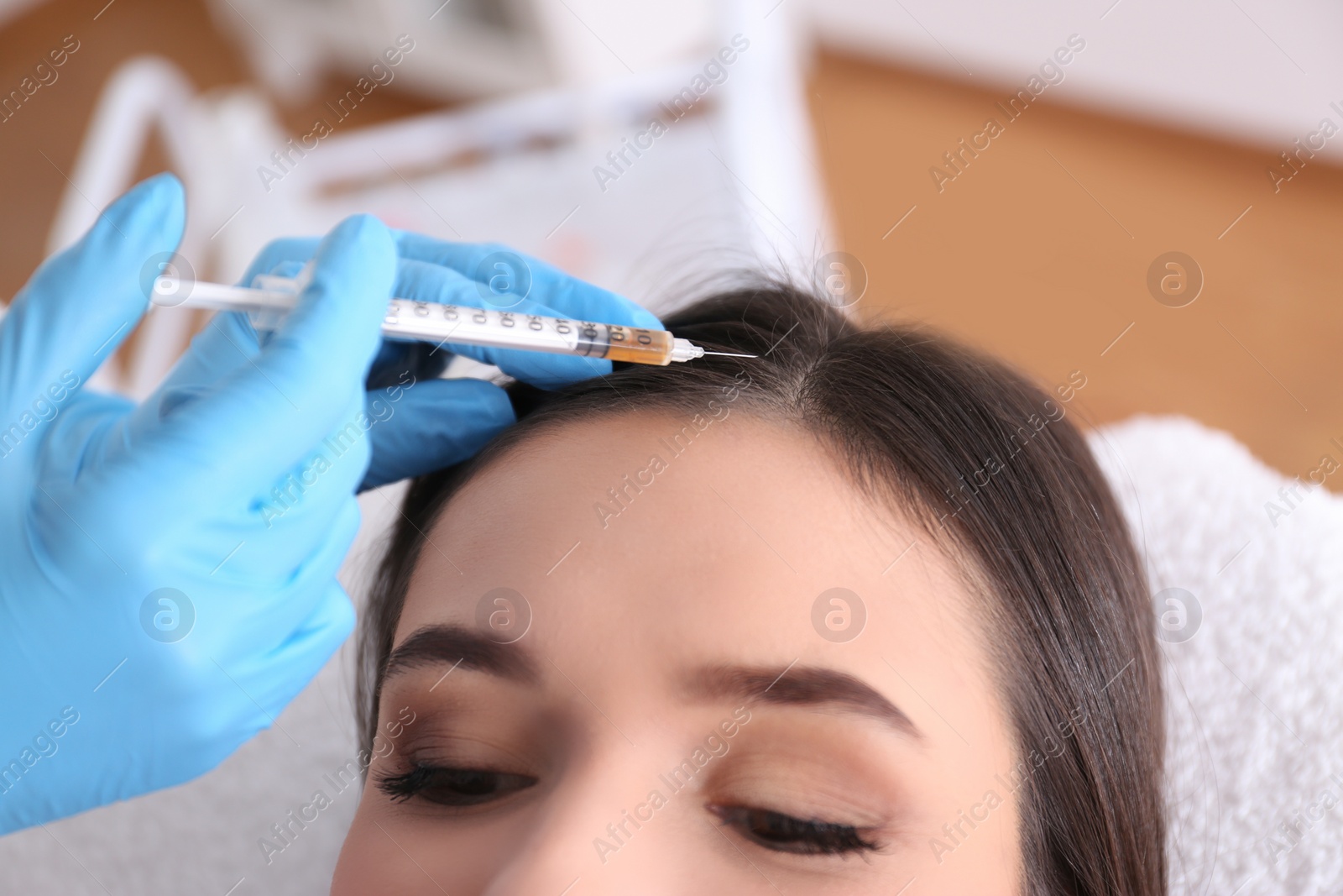 Photo of Young woman with hair loss problem receiving injection in salon, closeup