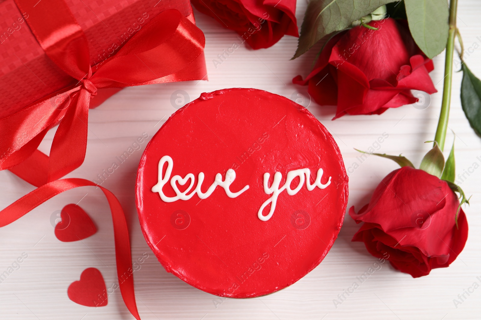 Photo of Bento cake with text Love You, gift box, roses and paper hearts on white wooden table, flat lay. St. Valentine's day surprise