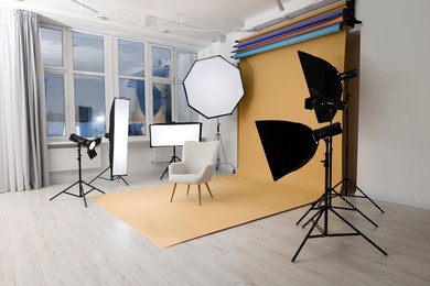 Interior of modern photo studio with armchair and professional lighting equipment