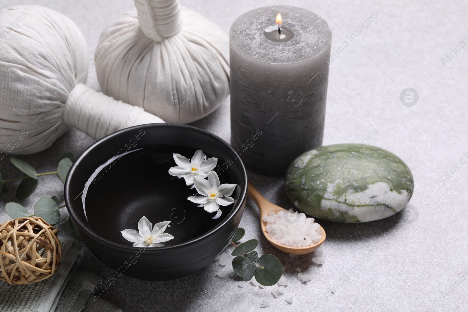 Photo of Beautiful composition with herbal massage bags, spa products and flowers on light grey table