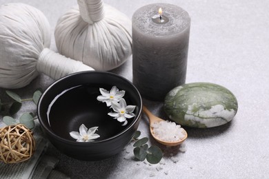 Photo of Beautiful composition with herbal massage bags, spa products and flowers on light grey table