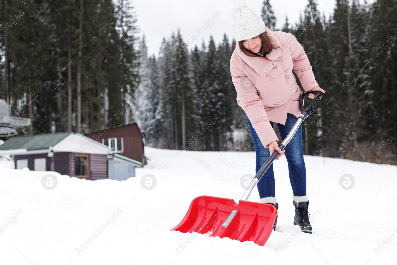 Photo of Woman removing snow with shovel near house. Space for text