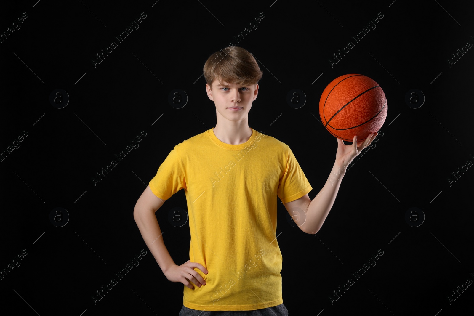 Photo of Teenage boy with basketball ball on black background