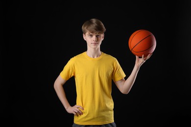 Photo of Teenage boy with basketball ball on black background