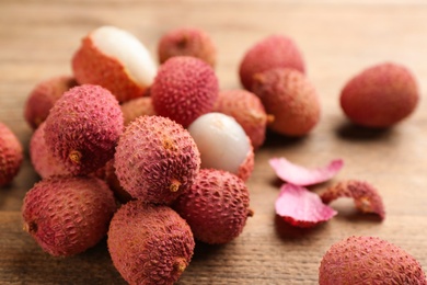 Photo of Fresh ripe lychees on wooden table, closeup. space for text