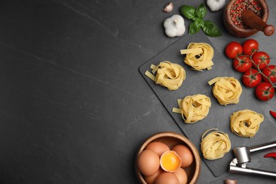 Photo of Flat lay composition with uncooked tagliatelle and fresh ingredients on black table. Space for text