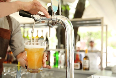Photo of Bartender pouring fresh cold beer from tap, closeup