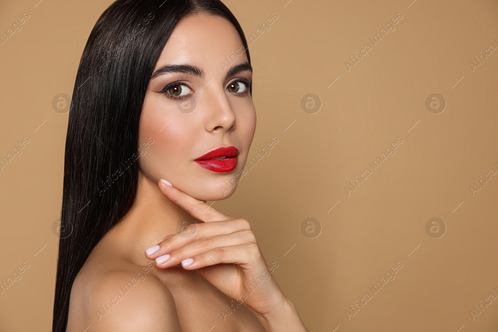 Photo of Portrait of young woman wearing beautiful red lipstick on beige background, space for text