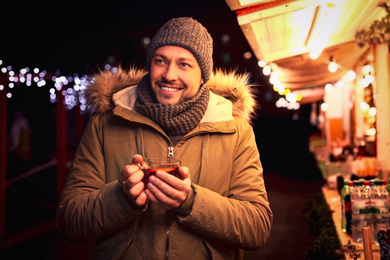 Happy man with mulled wine at winter fair