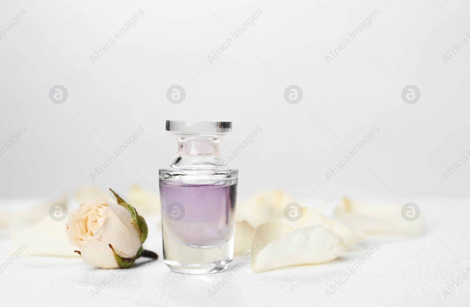 Photo of Perfume bottle and flower on table against light background