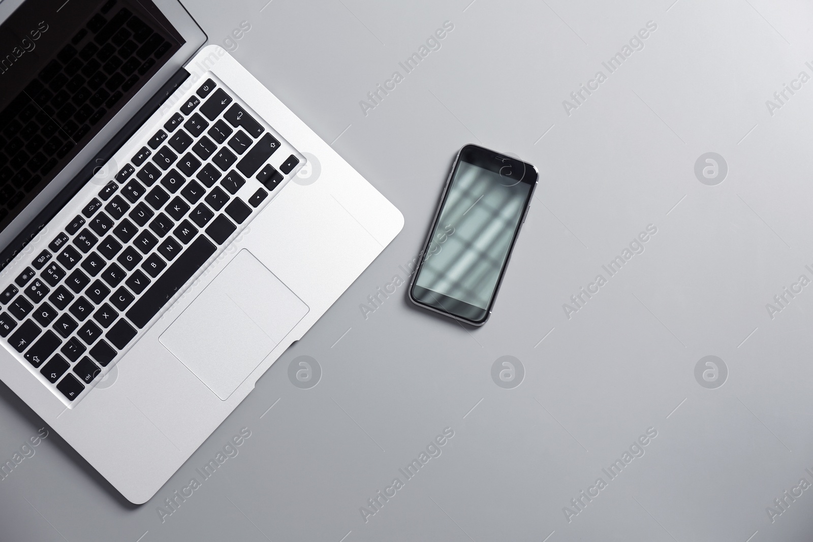 Photo of Modern laptop and mobile phone on gray background, top view