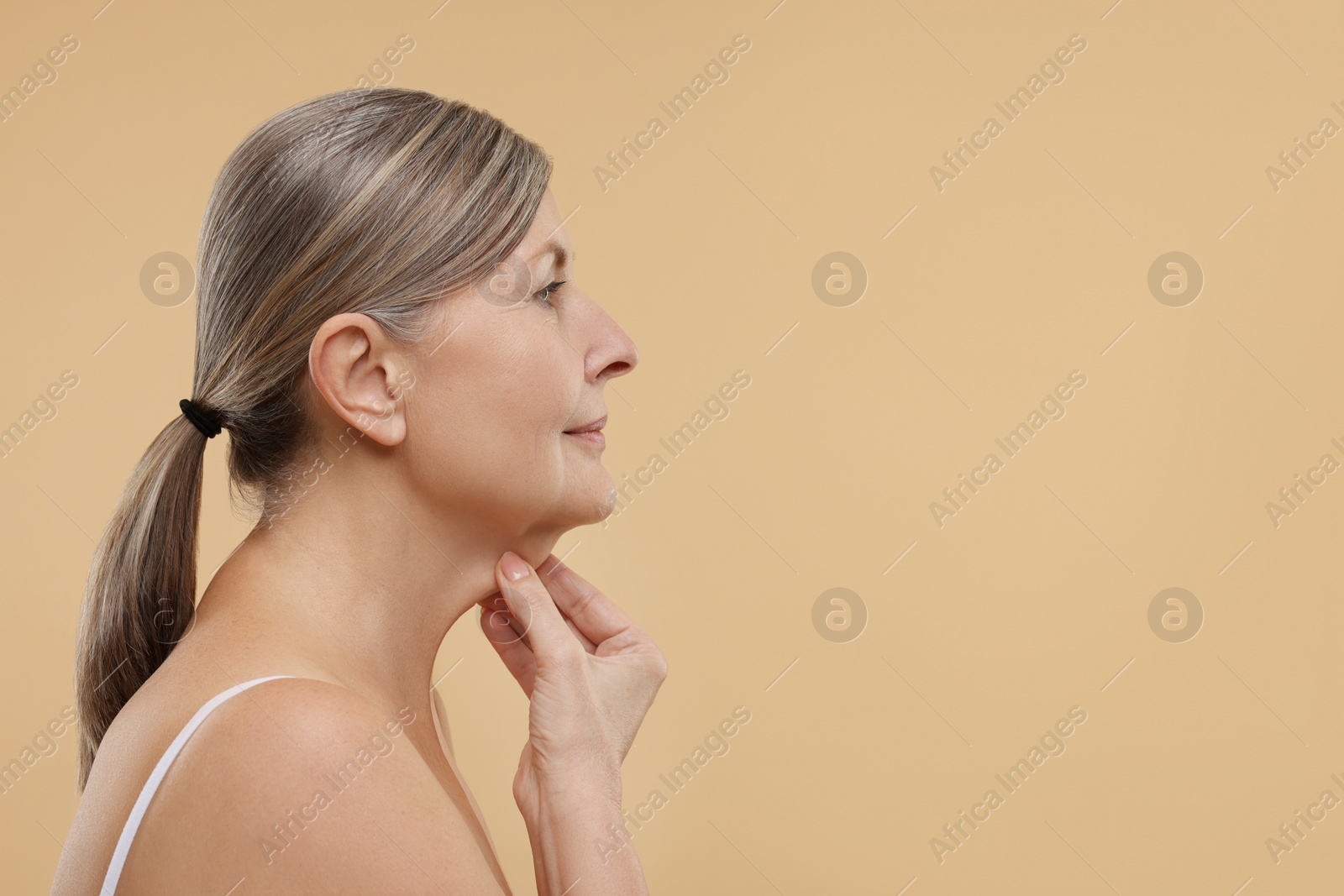 Photo of Beautiful woman touching her neck on beige background, space for text