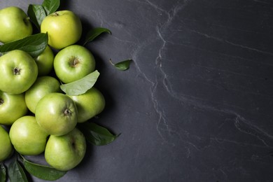 Photo of Ripe green apples with leaves on dark grey table, flat lay. Space for text