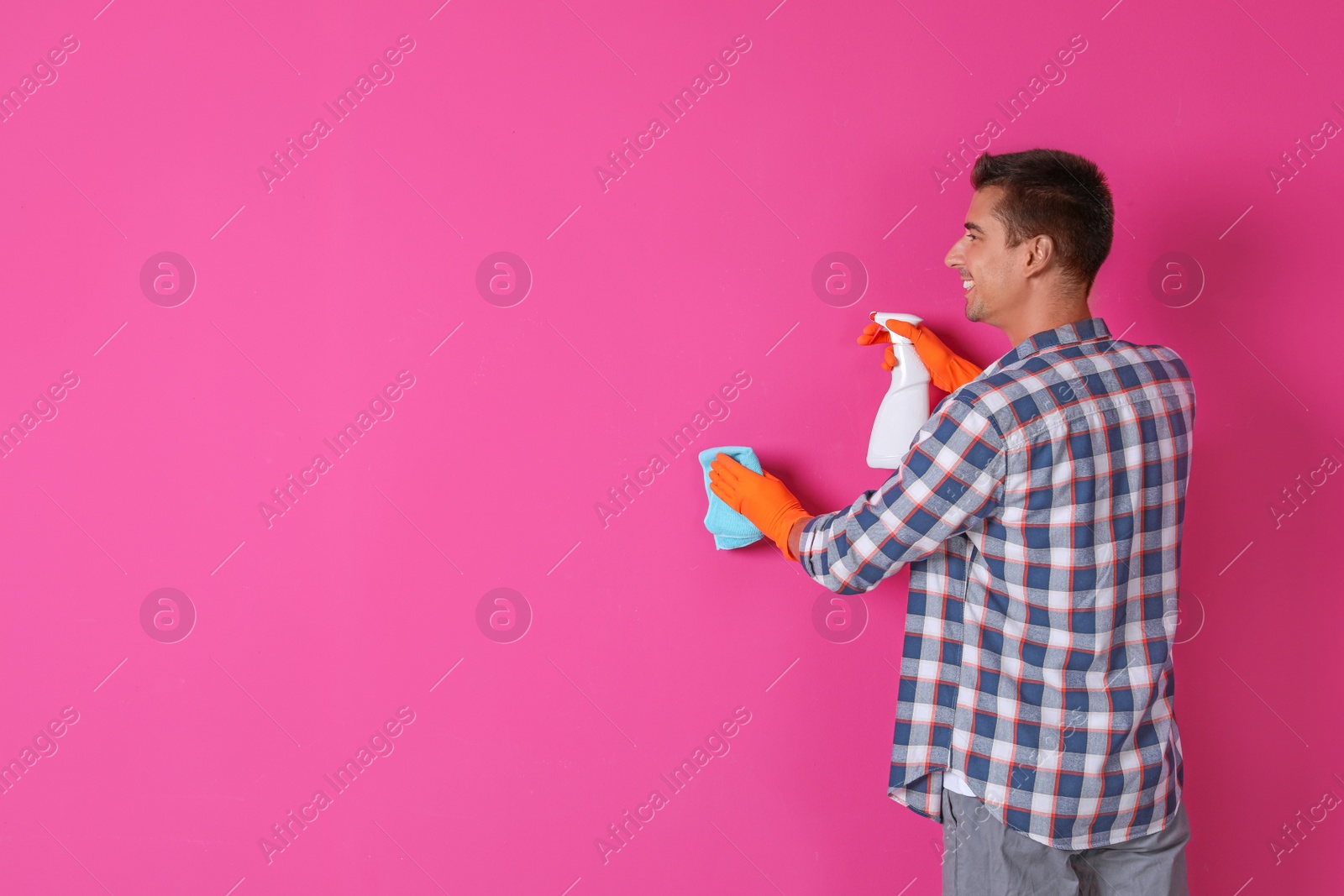 Photo of Man in gloves cleaning color wall with rag