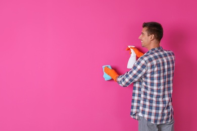 Photo of Man in gloves cleaning color wall with rag