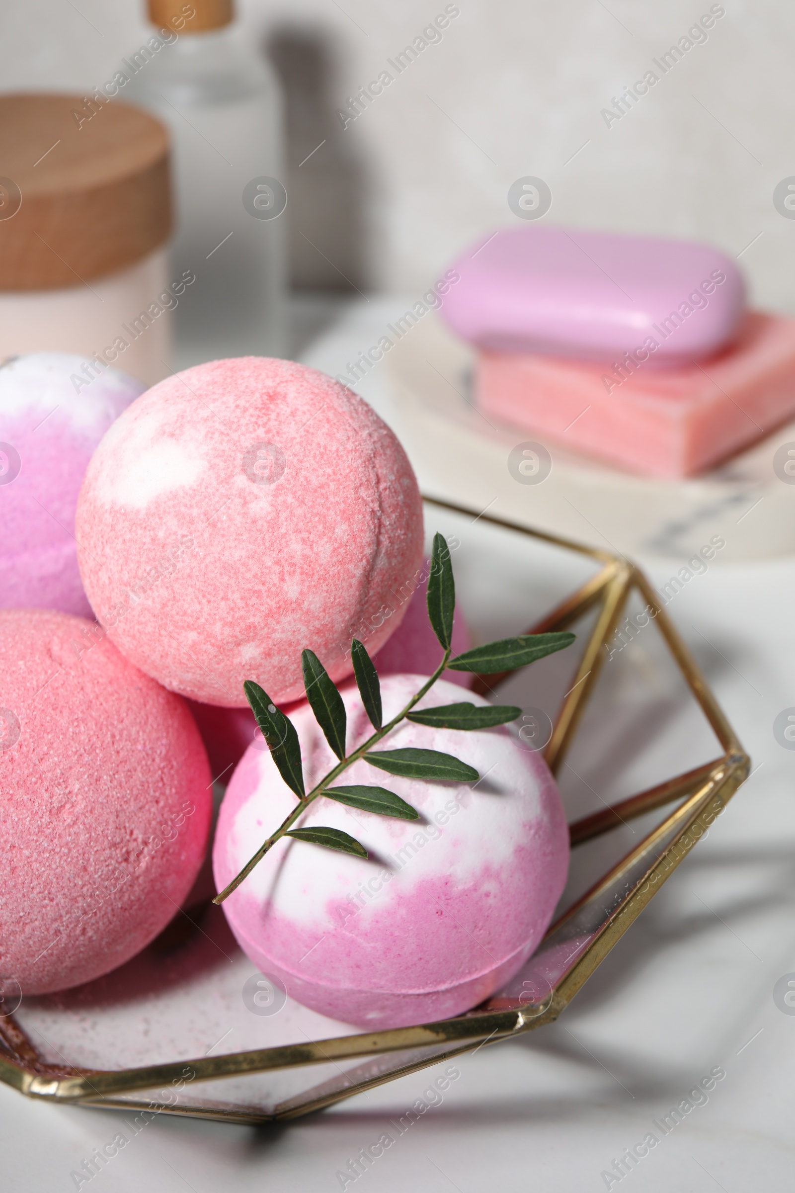 Photo of Beautiful aromatic bath bombs and green twig on white table, closeup