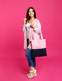 Full length portrait of young woman with textile bag on pink background
