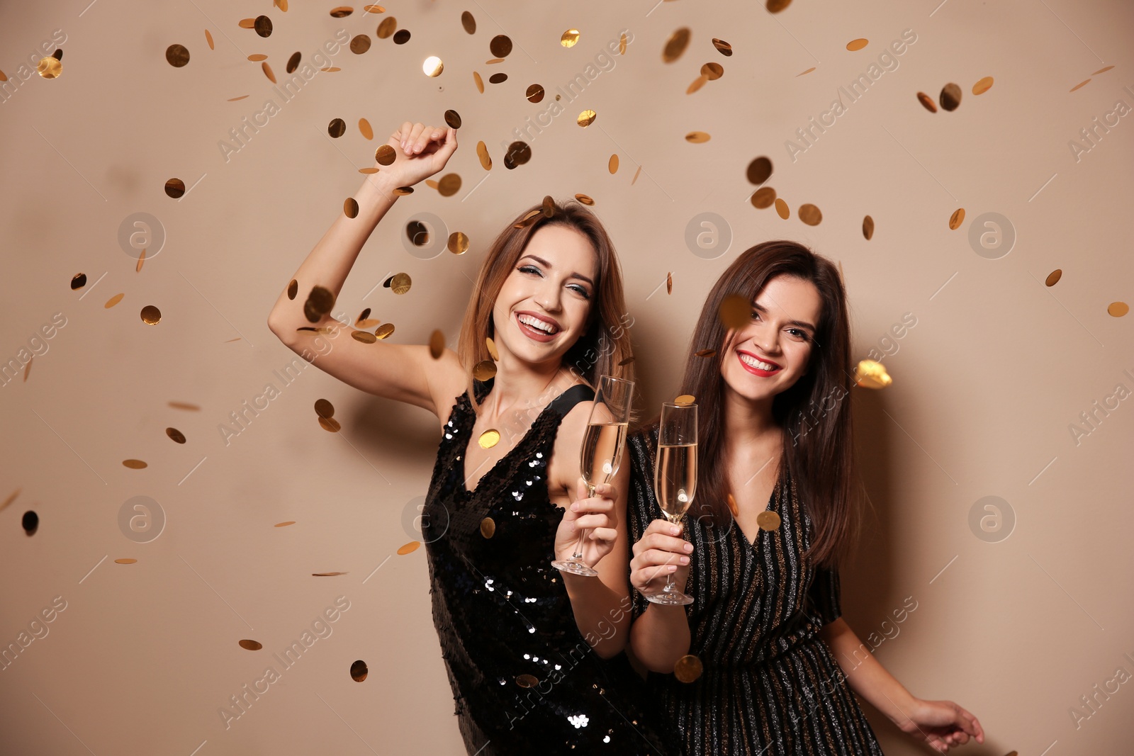 Photo of Beautiful women with glasses of champagne and confetti on color background