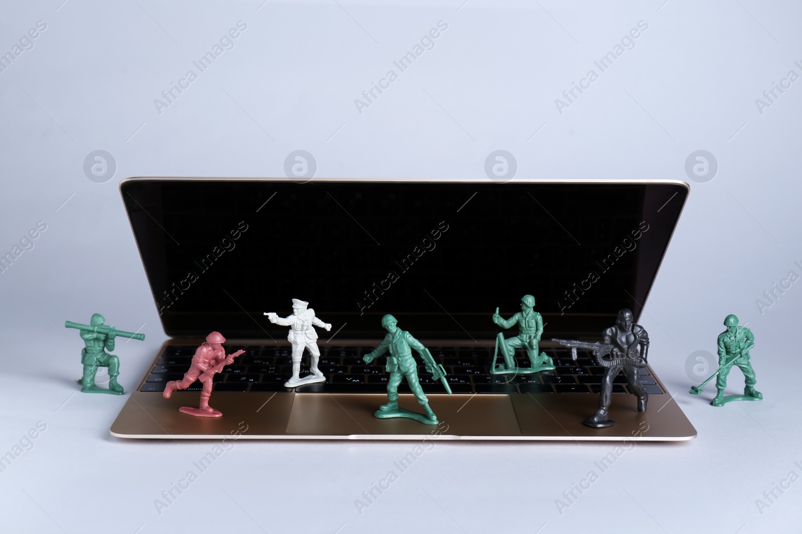 Photo of Hybrid warfare concept, online information battle. Laptop and toy soldiers on light grey background