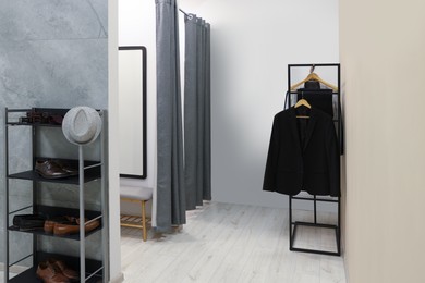 Photo of Dressing room with clothing rack in fashion store. Stylish design