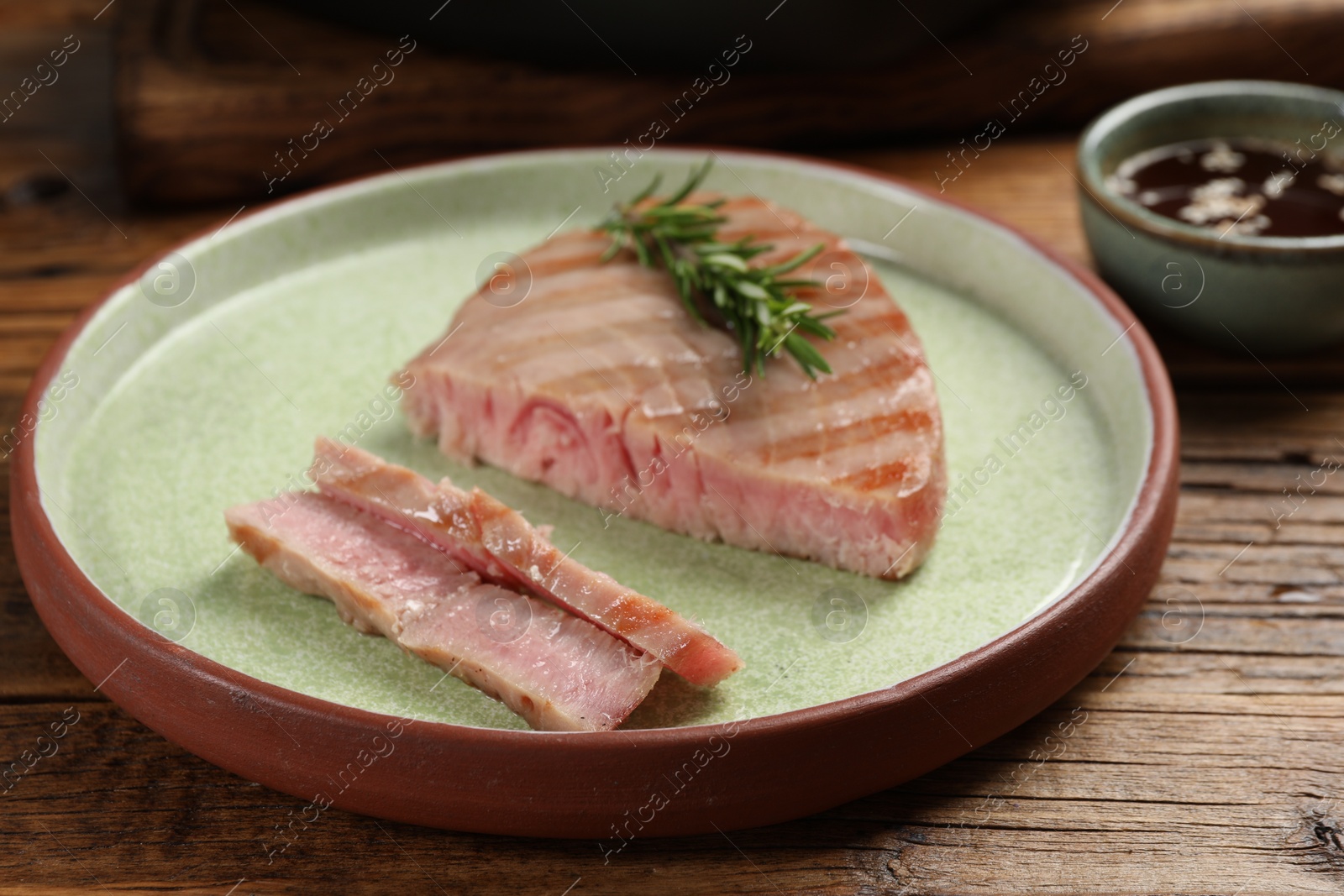 Photo of Delicious tuna steak with rosemary on wooden table, closeup
