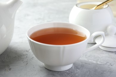 Tasty tea in cup on grey textured table, closeup