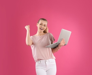 Photo of Portrait of young woman with laptop on pink background