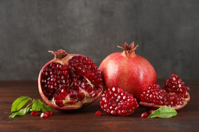 Photo of Fresh pomegranates and green leaves on wooden table