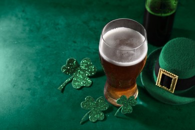 Image of St. Patrick's day. Beer, decorative clover leaves and leprechaun hat on green table, space for text