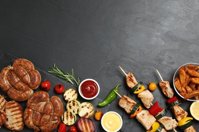 Flat lay composition with barbecued meat and vegetables on grey table. Space for text