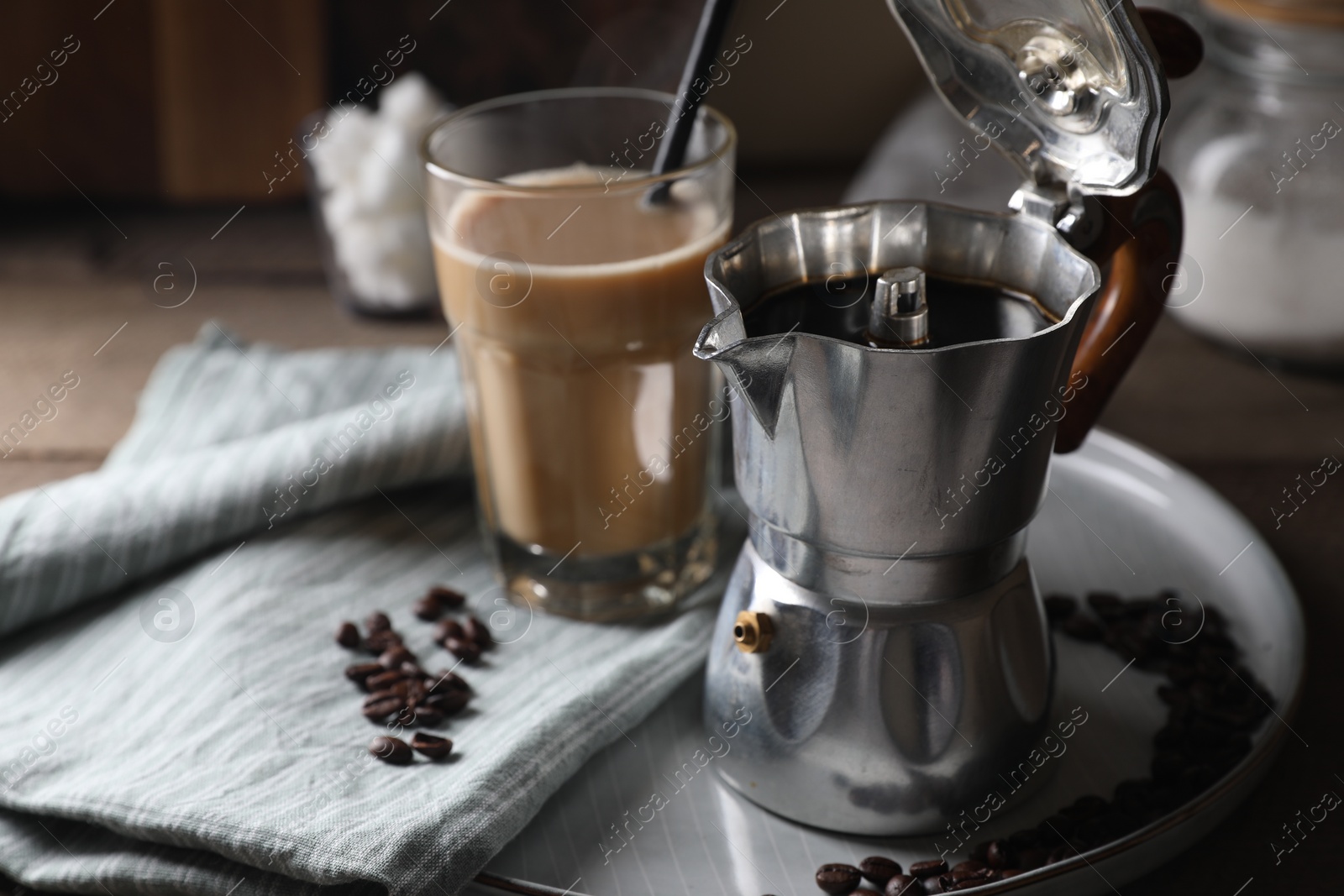 Photo of Brewed coffee in moka pot, glass of drink and beans on table