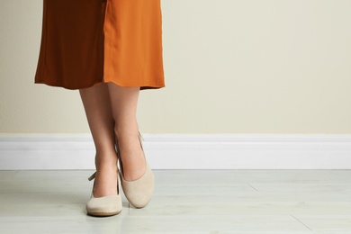 Photo of Woman wearing stylish shoes near beige wall indoors, closeup. Space for text