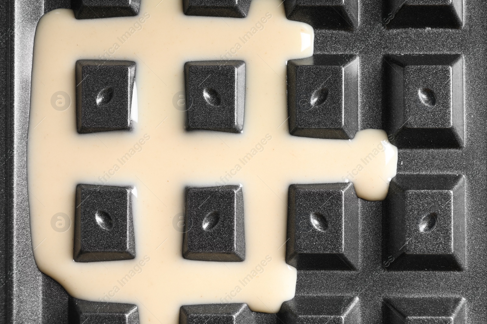 Photo of Belgian waffle maker with dough, top view