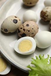 Unpeeled and peeled hard boiled quail eggs on plate, closeup