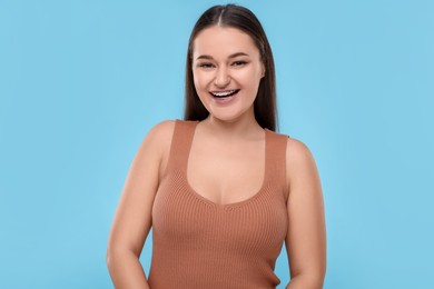 Happy woman with dental braces on light blue background