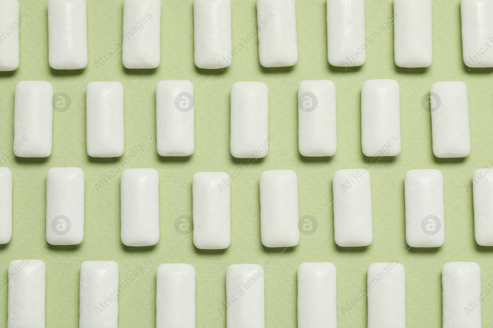 Photo of Tasty white chewing gums on light green background, flat lay