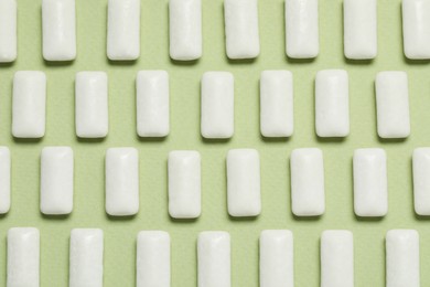 Photo of Tasty white chewing gums on light green background, flat lay