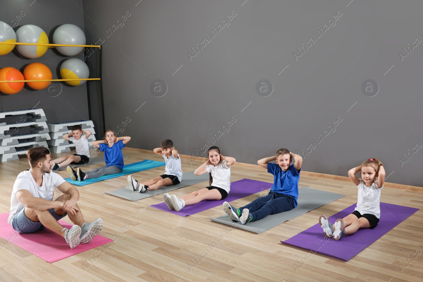 Photo of Cute little children and trainer doing physical exercise in school gym. Healthy lifestyle