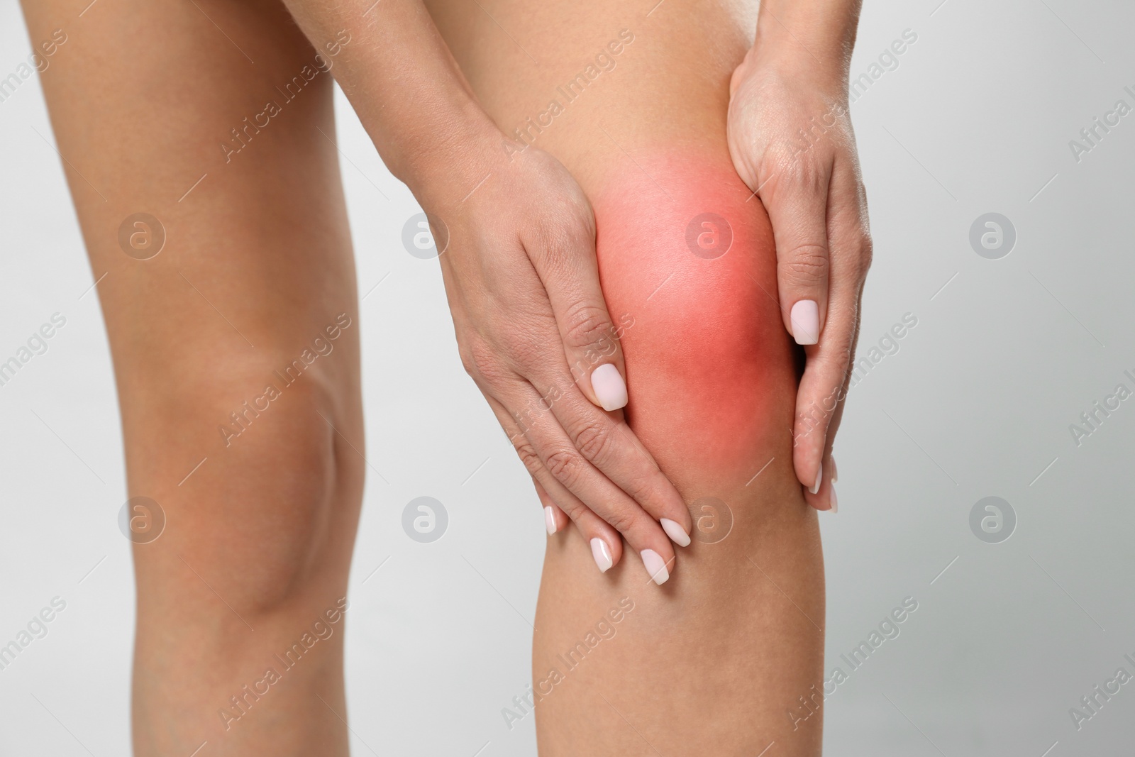 Photo of Woman having knee problems on grey background, closeup