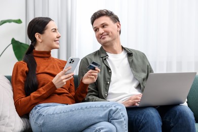 Happy couple with credit card and gadgets shopping online together at home