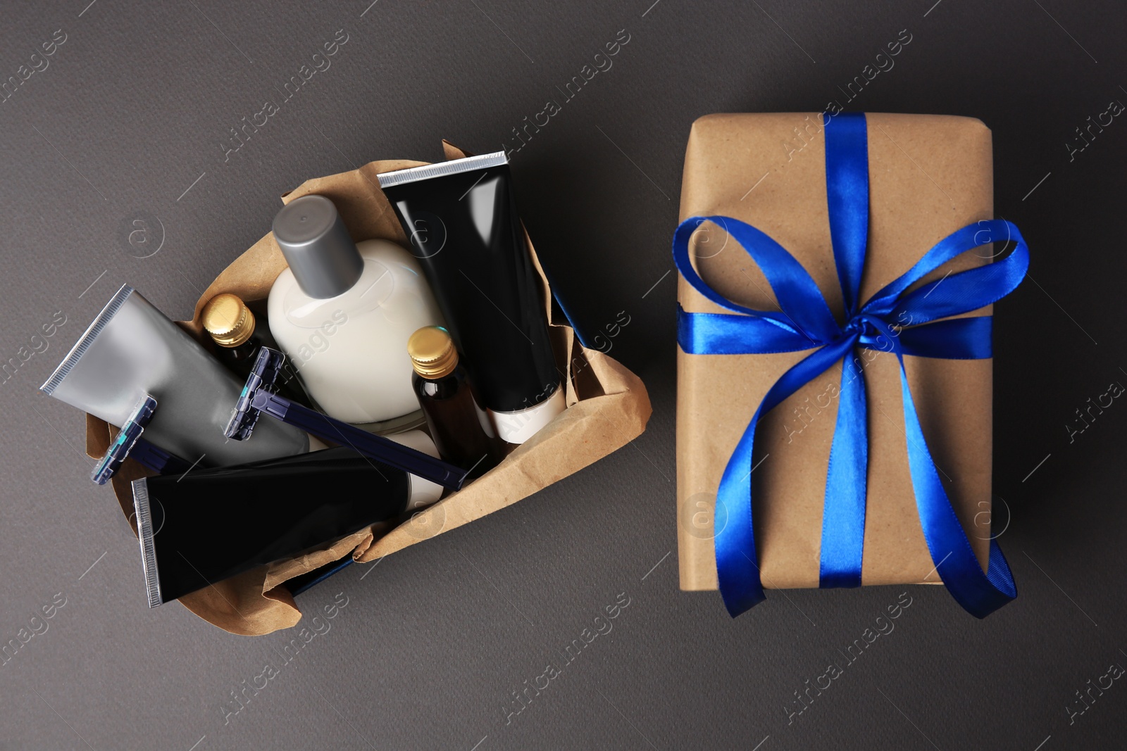 Photo of Gift box with different men's shaving accessories and cosmetics on dark grey background, flat lay