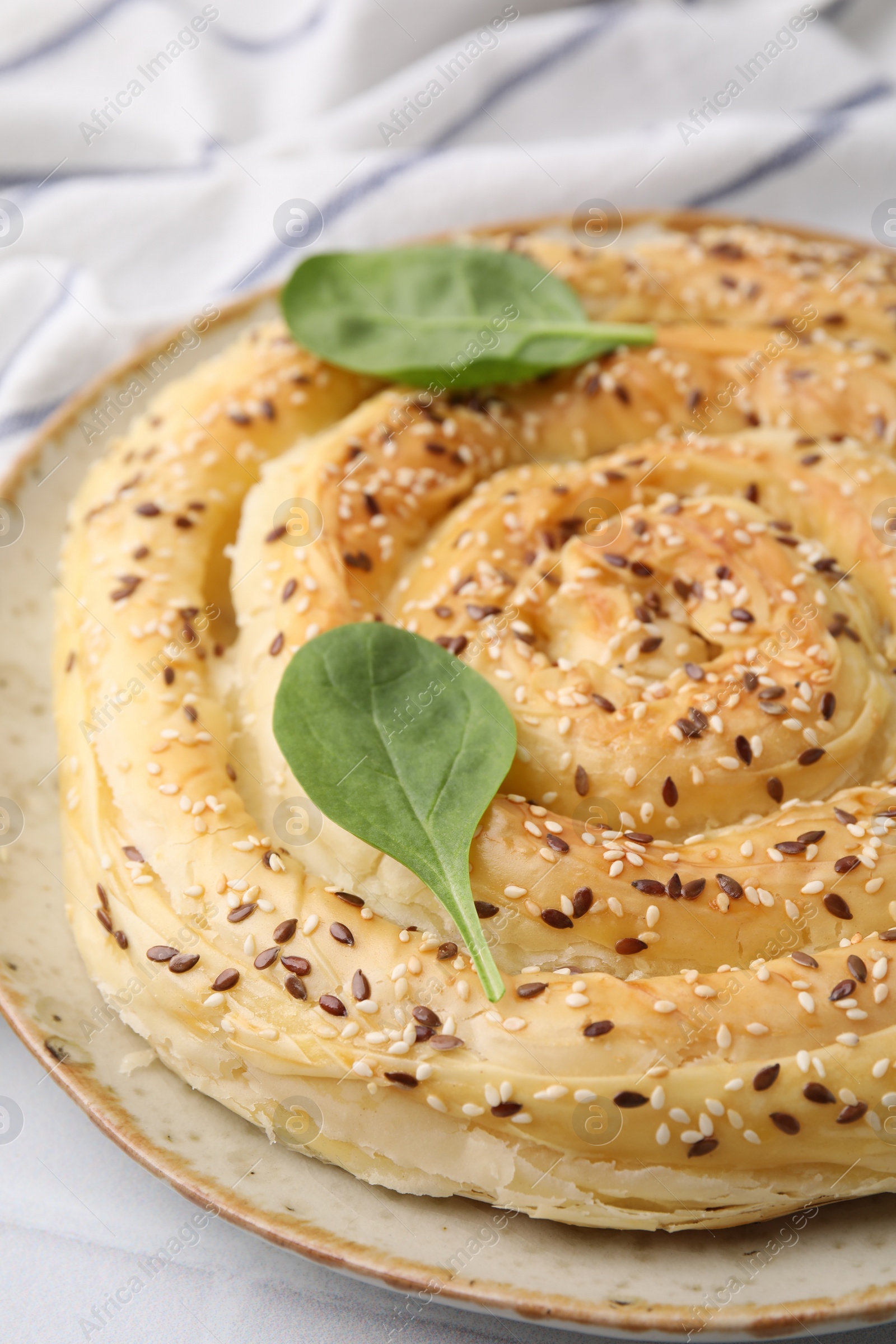 Photo of Delicious puff pastry with spinach on white tiled table, closeup