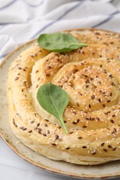 Photo of Delicious puff pastry with spinach on white tiled table, closeup