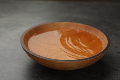 Photo of Wooden bowl with water on grey table, closeup