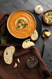 Flat lay composition with bowl of delicious pumpkin soup on grey textured table