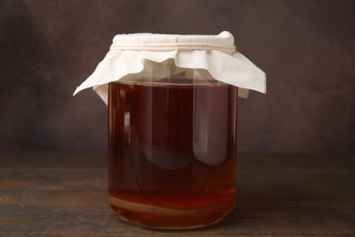 Photo of Tasty kombucha in glass jar on wooden table