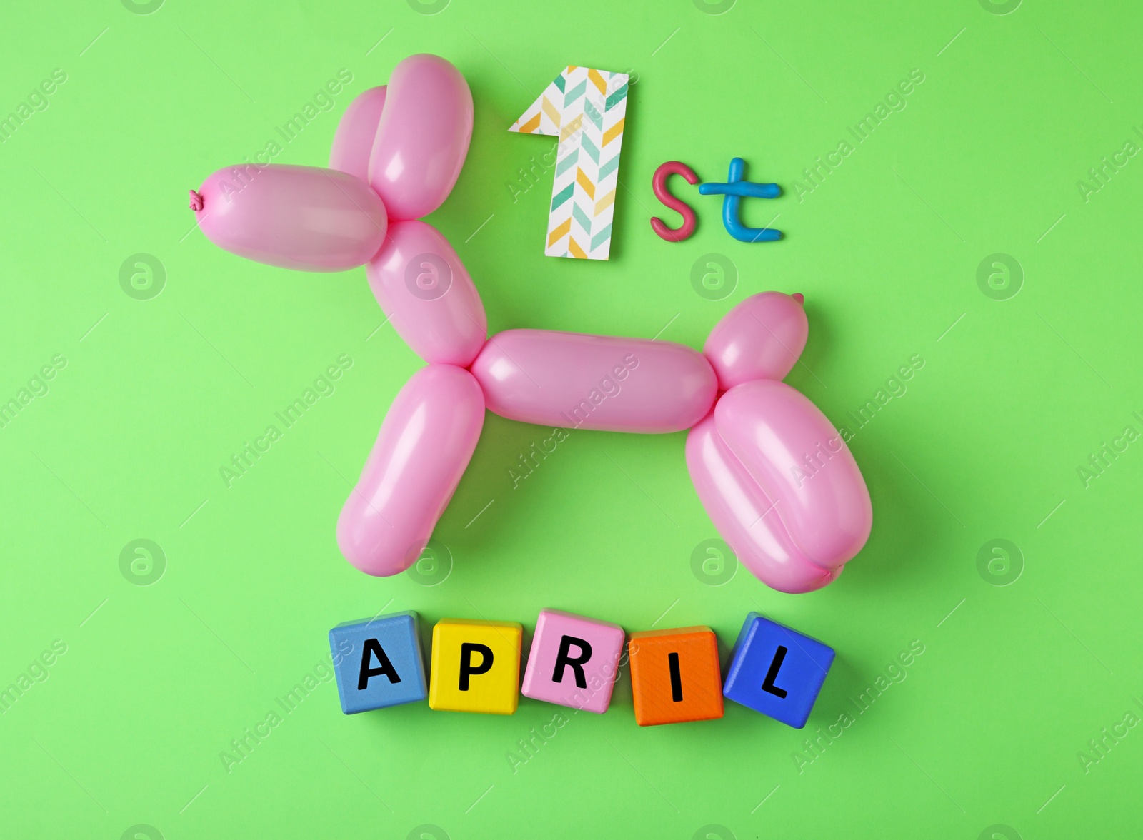 Photo of Balloon animal and phrase 1st APRIL on green background, flat lay. Fool's day