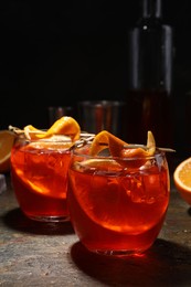 Photo of Aperol spritz cocktail, ice cubes and orange slices in glasses on grey textured table, closeup