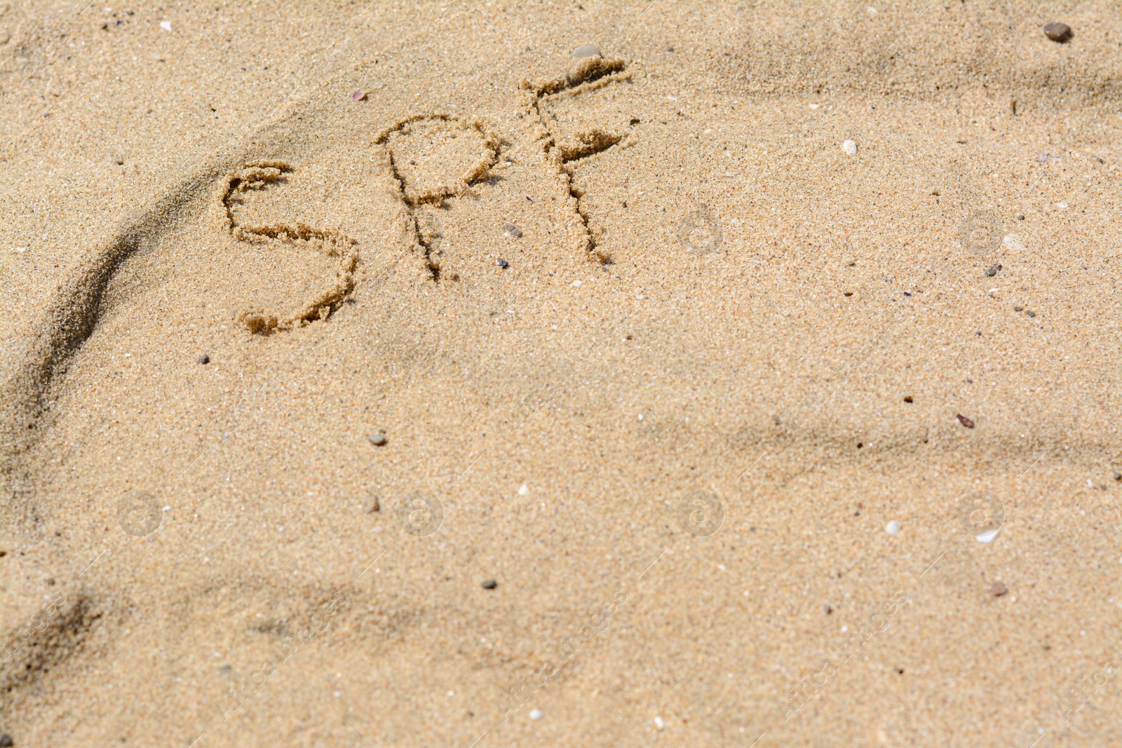 Photo of Abbreviation SPF written on sand at beach, above view. Space for text