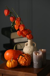Beautiful autumn composition with pumpkins and burning candles on wooden table indoors